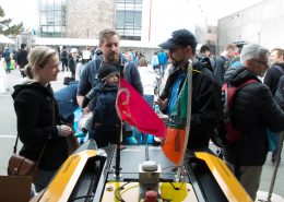 MIT AUV Lab's Paul Robinette talks to a couple with a baby about a yellow AUV on display