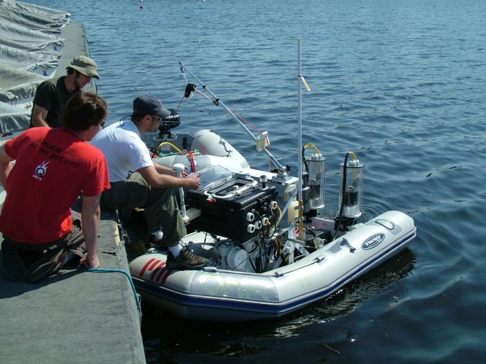 People on a dock adjusting parts on a surface vehicle