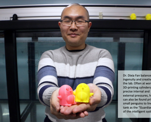 Dixia Fan, PhD, holding two 3D printed penguins, the Guardians of the Intelligent Towing Tank, which he is standing in front of