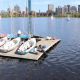 Sailboats on a dock at the MIT Sailing Pavilion with the Boston skyline in the background with the Charles River
