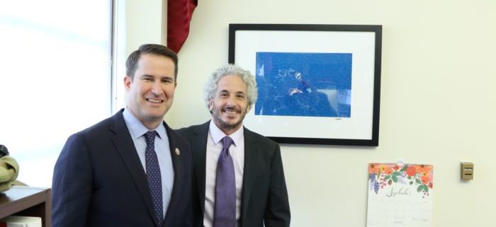 Congressman Seth Moulton and Keith Ellenbogen standing in front of a framed photograph of North Atlantic right whales.