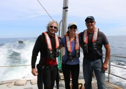 Underwater photographer Keith Ellenbogen stands on the back of a boat with a Knauss Fellow and the superintendent of Stellwagen Bank.