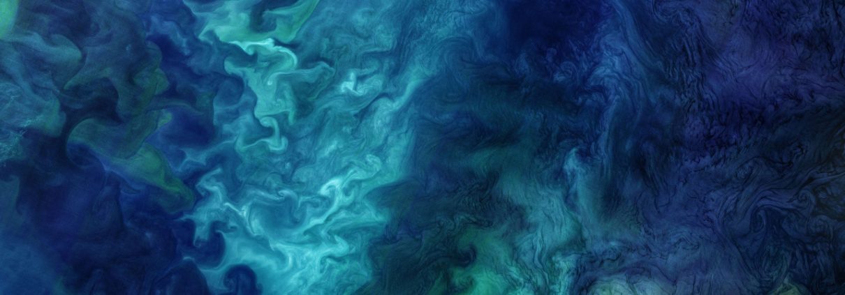 An aerial image of the ocean with swirling green and blue colors