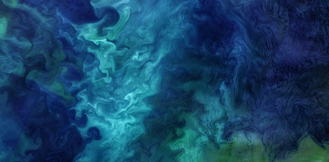 An aerial image of the ocean with swirling green and blue colors