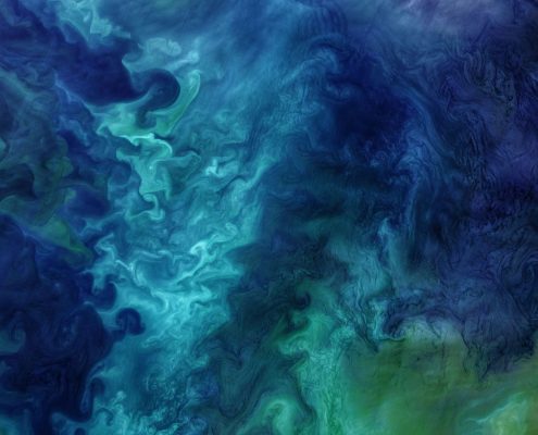 An aerial image of the ocean with swirling green and blue colors
