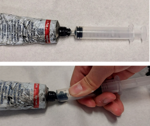 Carbon grease tube with syringe inserted; pulling carbon grease into the syringe