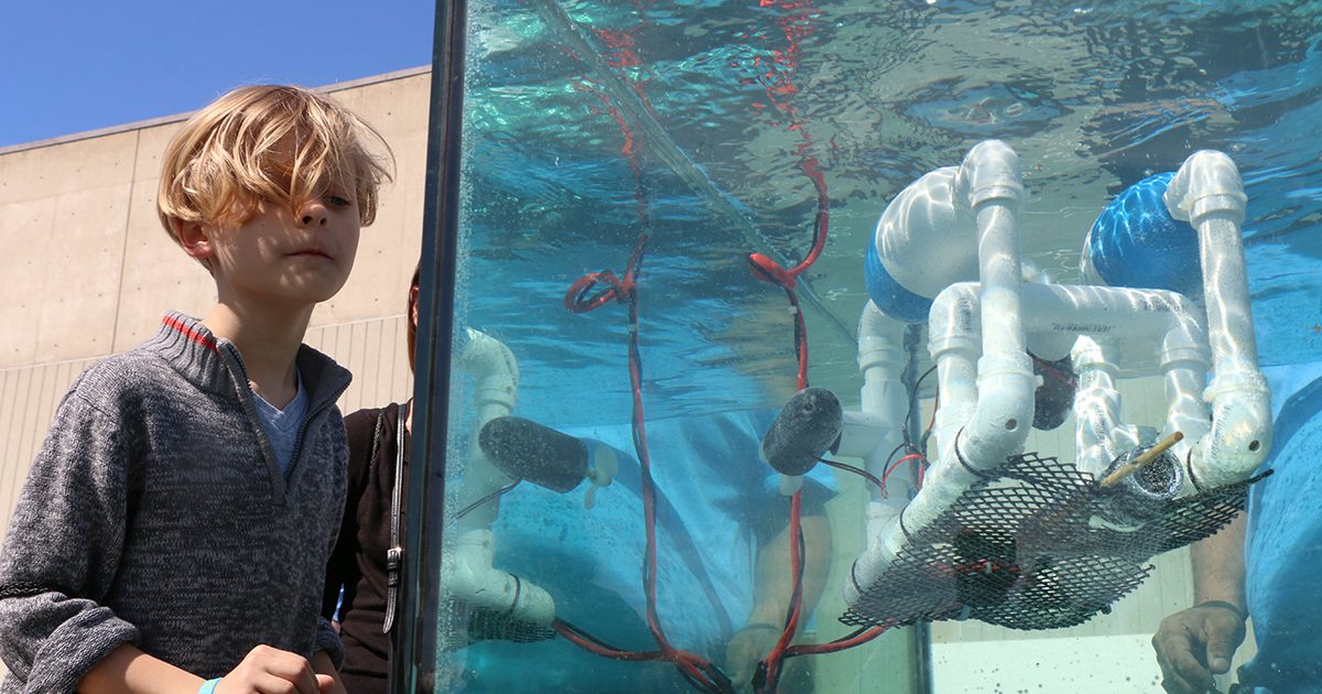 Young student operates an underwater robot in a tank