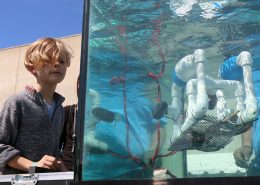 Young student operates an underwater robot in a tank