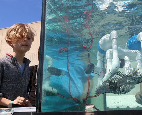 Young student operates an underwater robot in a tank