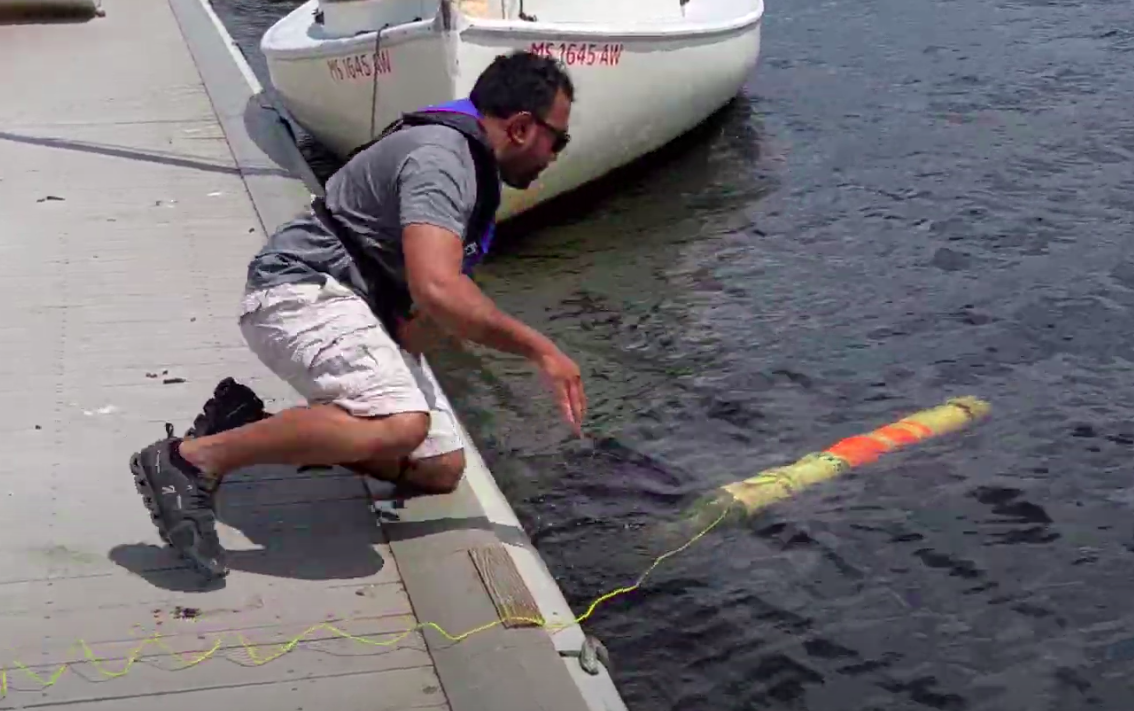 AUV Lab engineer submerges Sea Badger into the Charles River from a dock