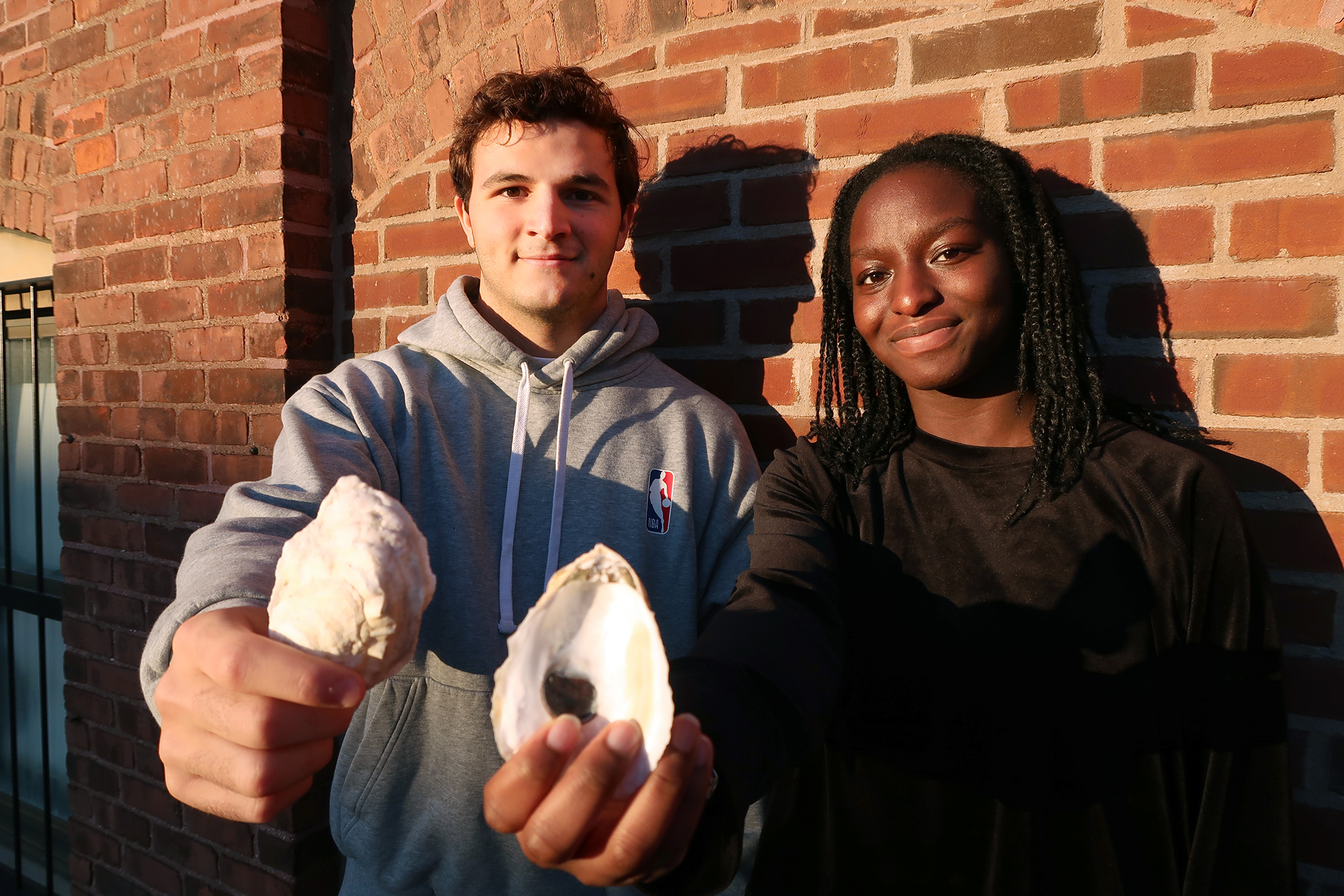 MIT Sea Grant students Santiago Borrego and Unyime Usua hold oyster shells.