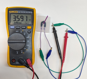 Multimeter connected to whisker sensor and showing resistance of 3.591 k ohms