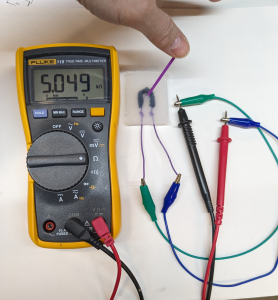 Swab deflected and multimeter showing resistance of 5.049 k ohms