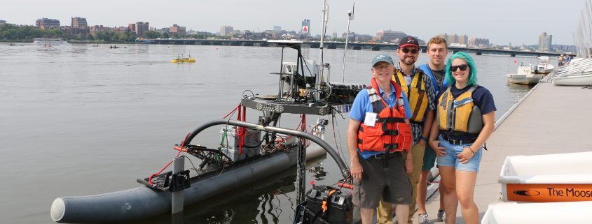 MIT AUV Lab team stands by REX, one of their autonomous vehicles, at the boat dock