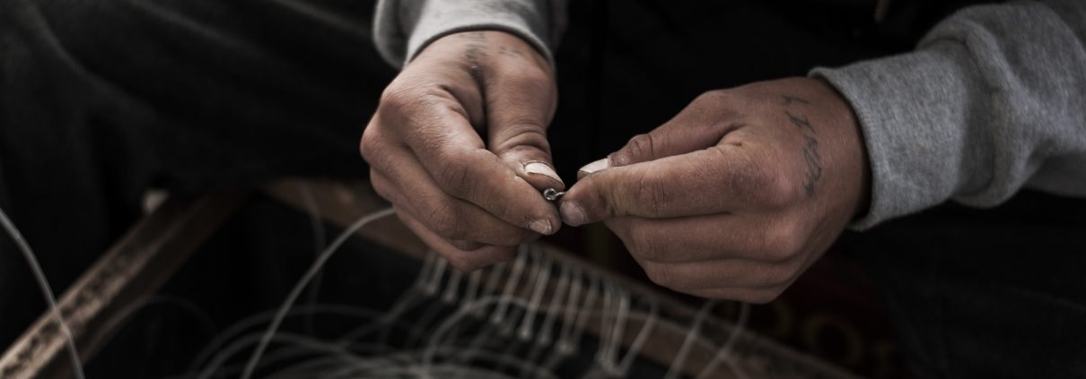 Two hands tying knots in fishing line